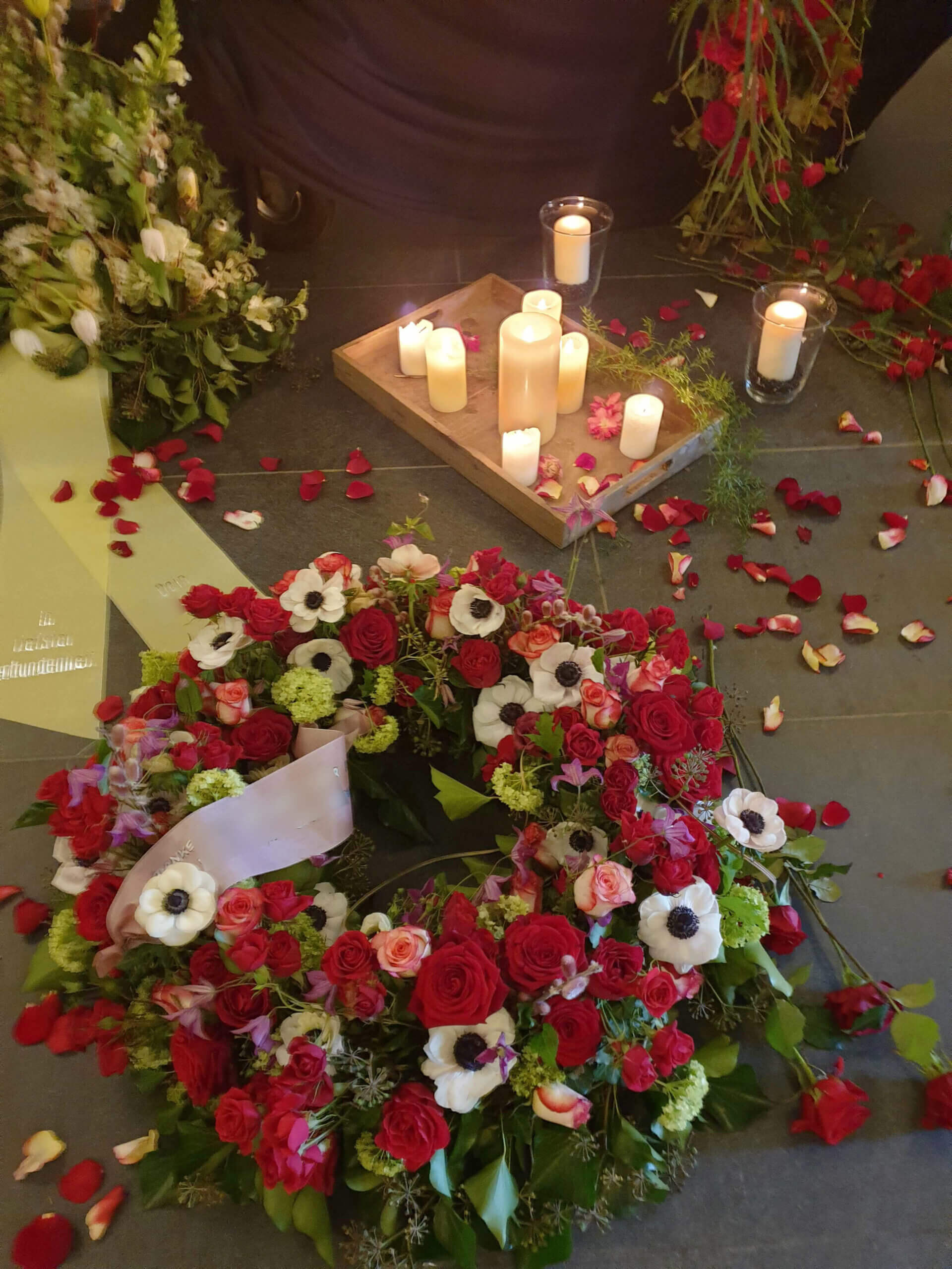 Roter Trauerkranz mit Rosen und Kerzen